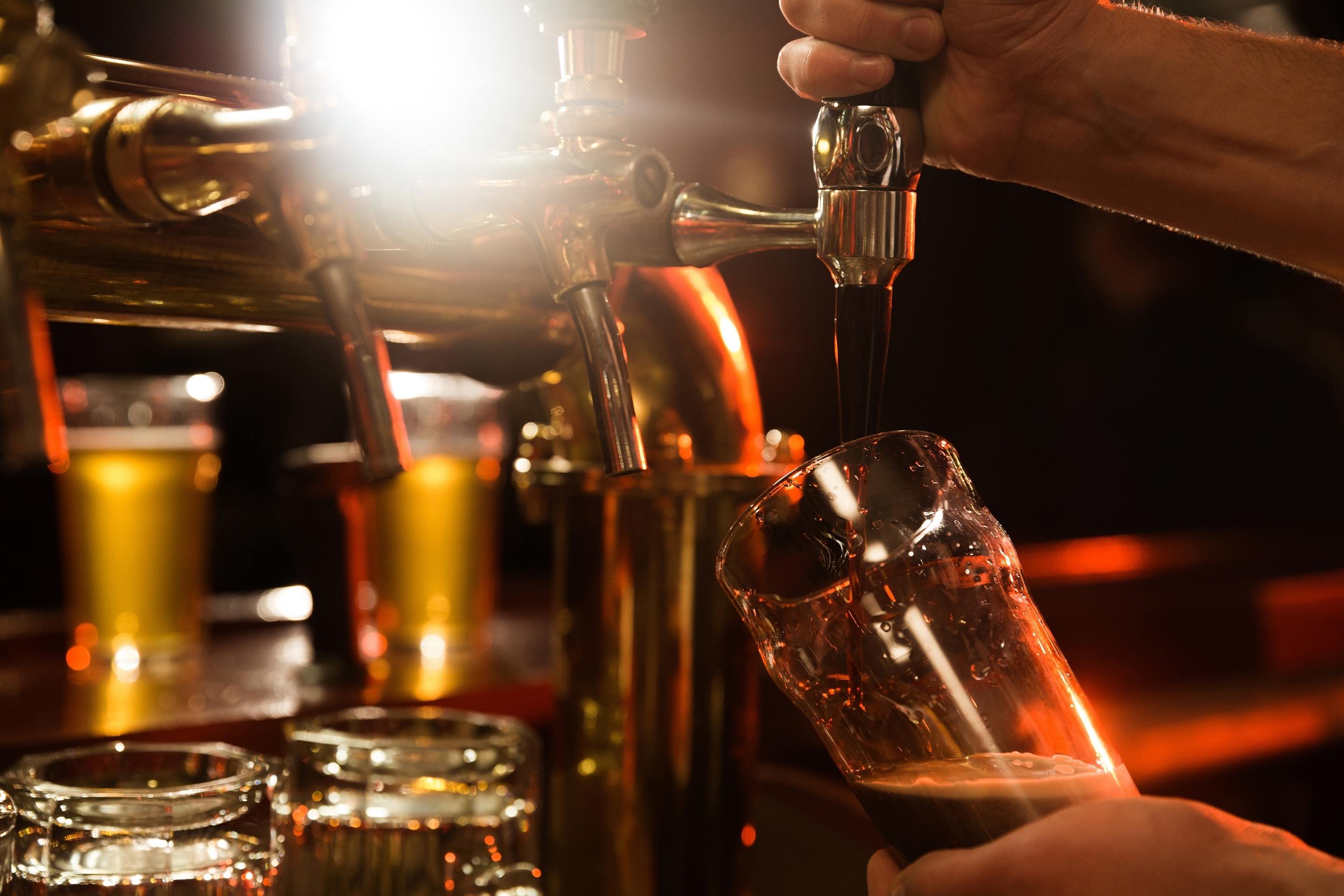 Närbild på en bartender som häller upp öl